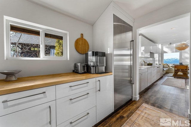 kitchen with dark wood-style floors, butcher block countertops, high end refrigerator, and white cabinetry