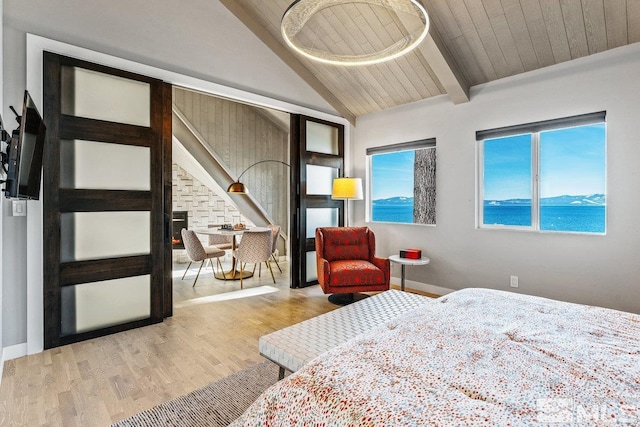 bedroom with light wood finished floors, a water view, lofted ceiling with beams, wooden ceiling, and baseboards