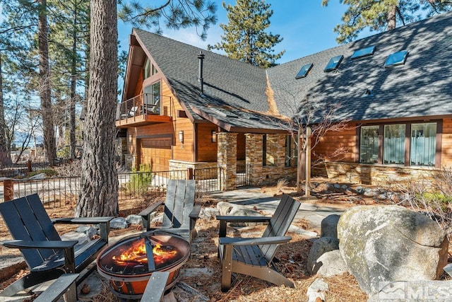 exterior space with a balcony, an outdoor fire pit, and a garage