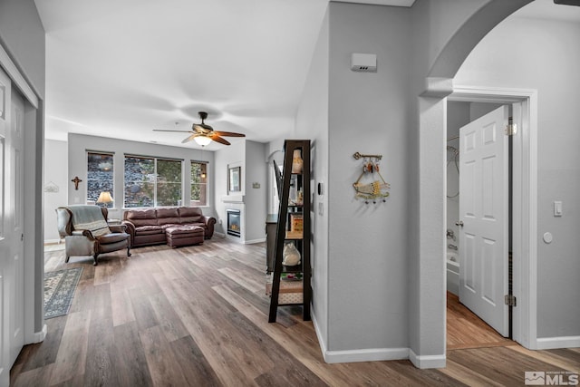 living area with baseboards, arched walkways, and wood finished floors