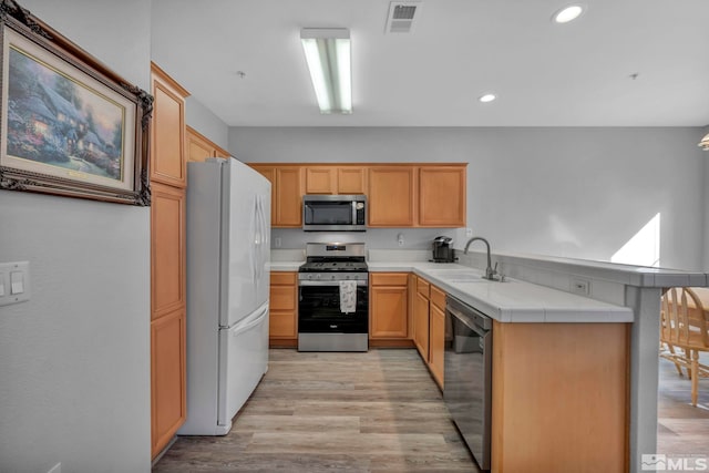 kitchen with a peninsula, a sink, visible vents, light countertops, and appliances with stainless steel finishes