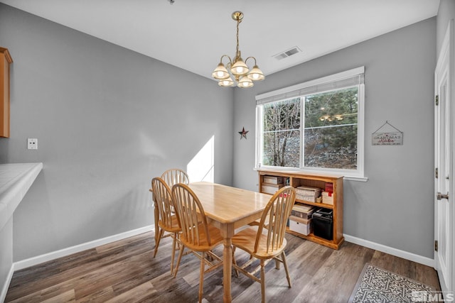 dining space with a chandelier, wood finished floors, visible vents, and baseboards