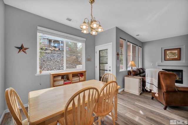 dining room with baseboards, visible vents, a tile fireplace, light wood-type flooring, and a notable chandelier