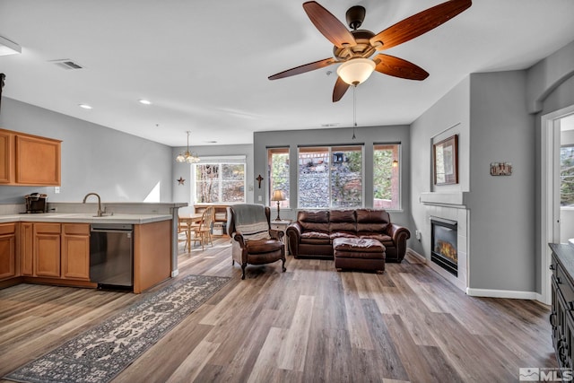 living area with a healthy amount of sunlight, light wood-style flooring, visible vents, and a tiled fireplace