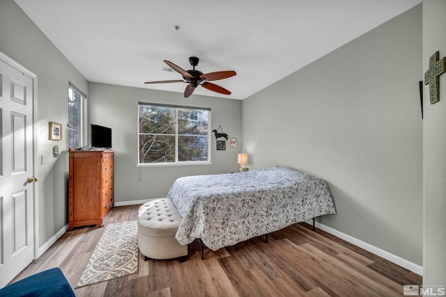 bedroom featuring a ceiling fan, baseboards, and wood finished floors