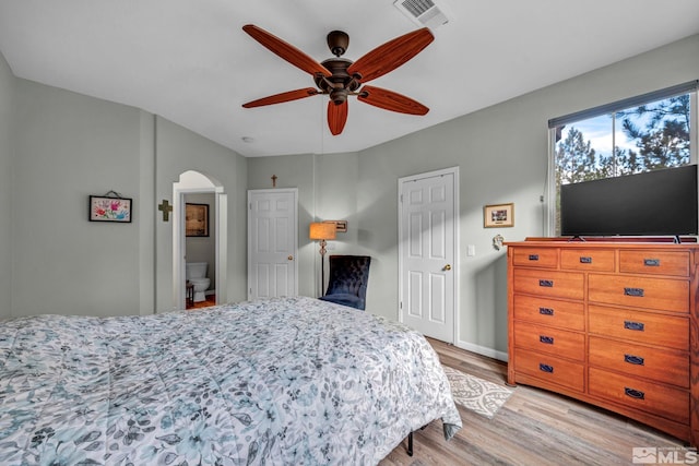 bedroom featuring arched walkways, light wood finished floors, visible vents, a ceiling fan, and baseboards