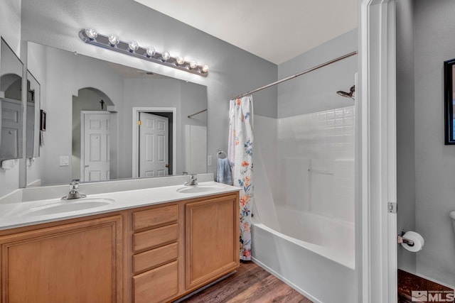 bathroom with shower / tub combo, double vanity, a sink, and wood finished floors