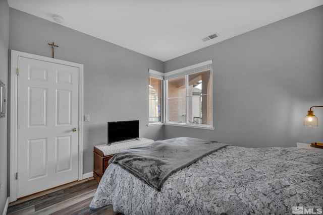 bedroom featuring visible vents, baseboards, and wood finished floors