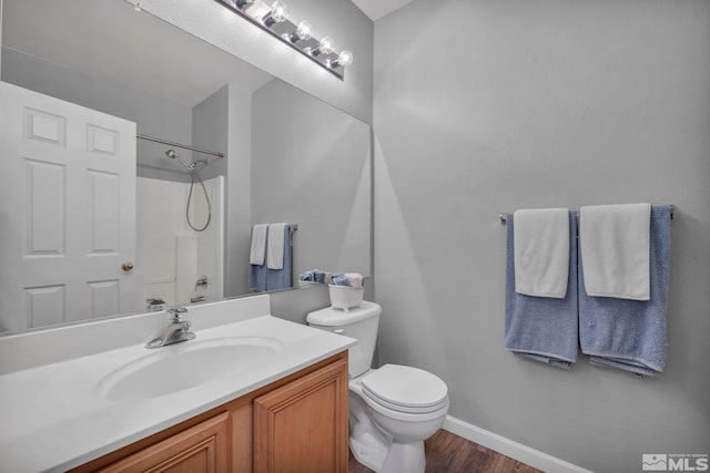 full bathroom with toilet, wood finished floors, vanity, baseboards, and walk in shower