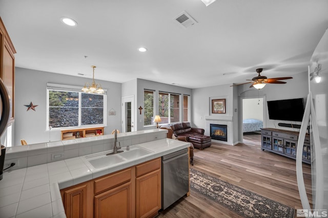 kitchen with tile countertops, a sink, visible vents, open floor plan, and dishwasher