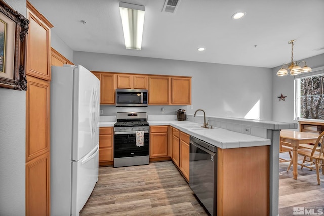 kitchen featuring a peninsula, a sink, visible vents, appliances with stainless steel finishes, and pendant lighting