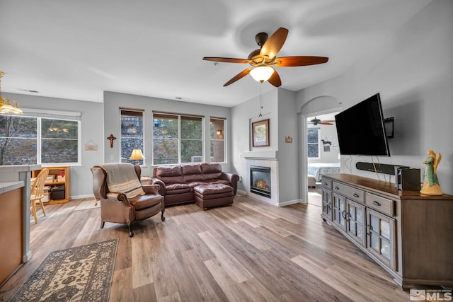 living room featuring a healthy amount of sunlight, a fireplace, light wood-style flooring, and baseboards