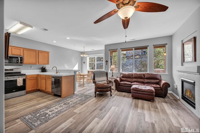 kitchen with a peninsula, stainless steel appliances, visible vents, open floor plan, and light countertops