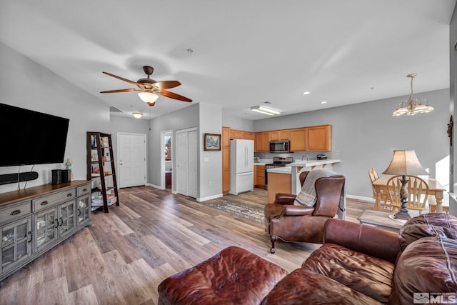 living area with light wood-style floors, recessed lighting, baseboards, and ceiling fan with notable chandelier