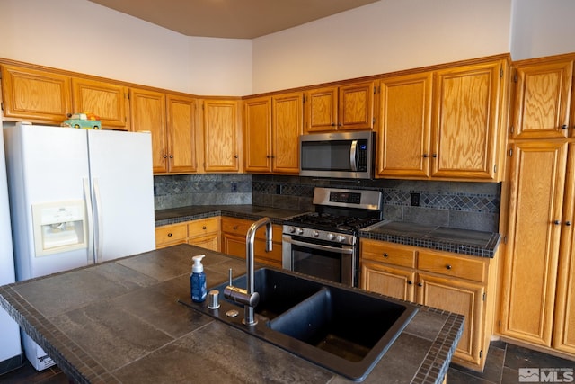 kitchen with dark countertops, decorative backsplash, stainless steel appliances, and a sink