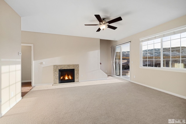 unfurnished living room featuring a fireplace with flush hearth, carpet, a mountain view, and baseboards