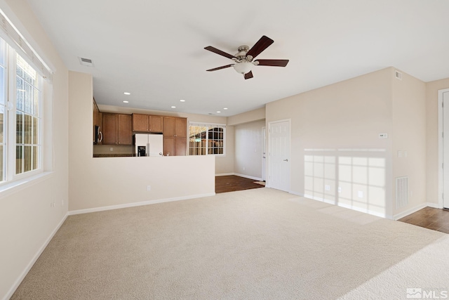 unfurnished living room featuring visible vents, dark colored carpet, a wealth of natural light, and recessed lighting