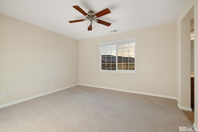 carpeted spare room with ceiling fan, visible vents, and baseboards