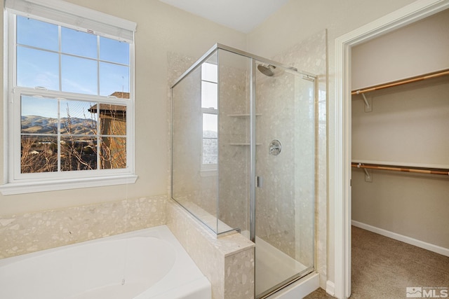 full bath with a garden tub, a spacious closet, a shower stall, and baseboards