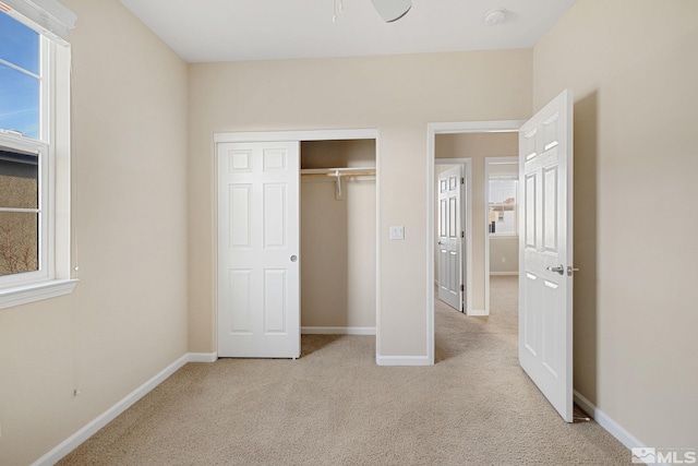 unfurnished bedroom featuring baseboards, a closet, and light colored carpet