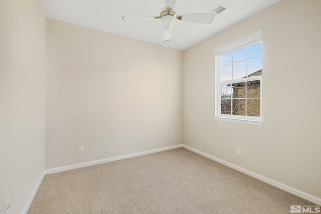 carpeted spare room featuring ceiling fan, visible vents, and baseboards