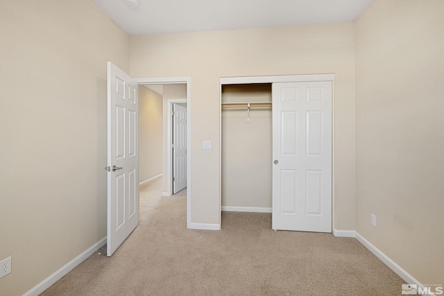 unfurnished bedroom featuring light carpet, baseboards, and a closet