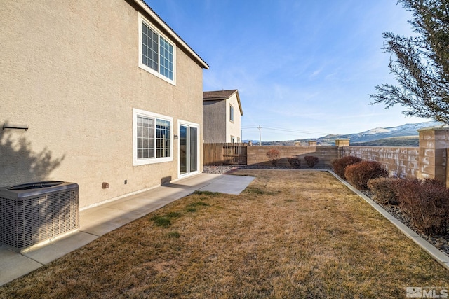 view of yard with a fenced backyard, a mountain view, and central air condition unit