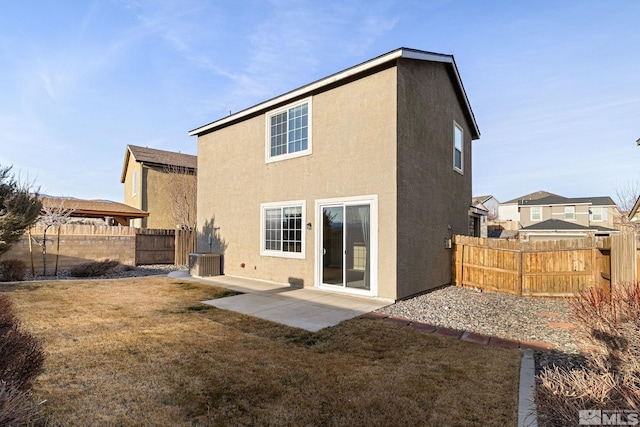 rear view of house with a yard, a patio, stucco siding, central AC unit, and a fenced backyard