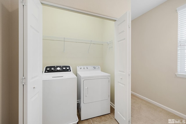 clothes washing area with laundry area, baseboards, separate washer and dryer, and light tile patterned flooring