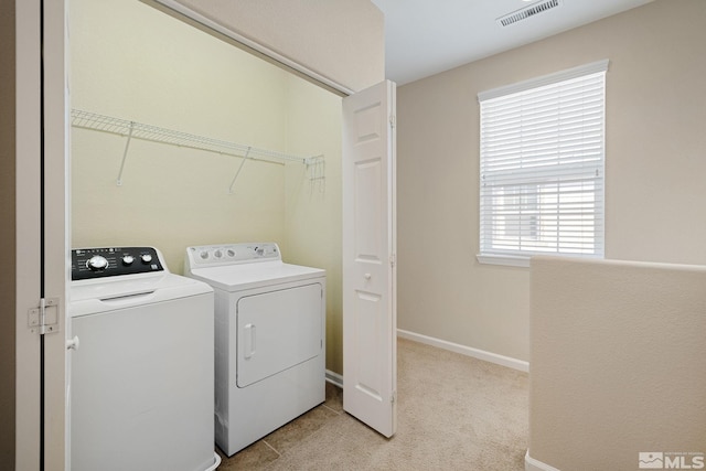 clothes washing area featuring washing machine and clothes dryer, light colored carpet, visible vents, laundry area, and baseboards