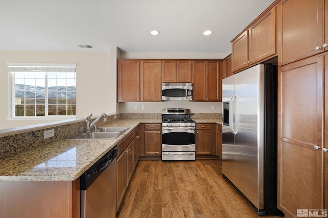 kitchen featuring a mountain view, a sink, appliances with stainless steel finishes, light wood-type flooring, and brown cabinets