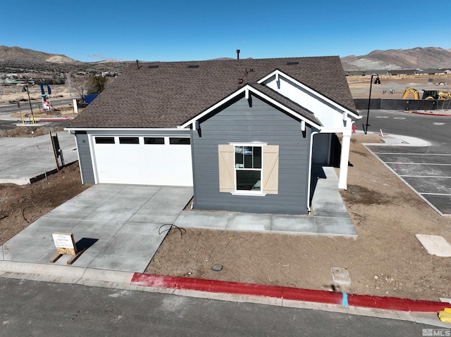 view of front of property with a garage, a mountain view, and roof with shingles