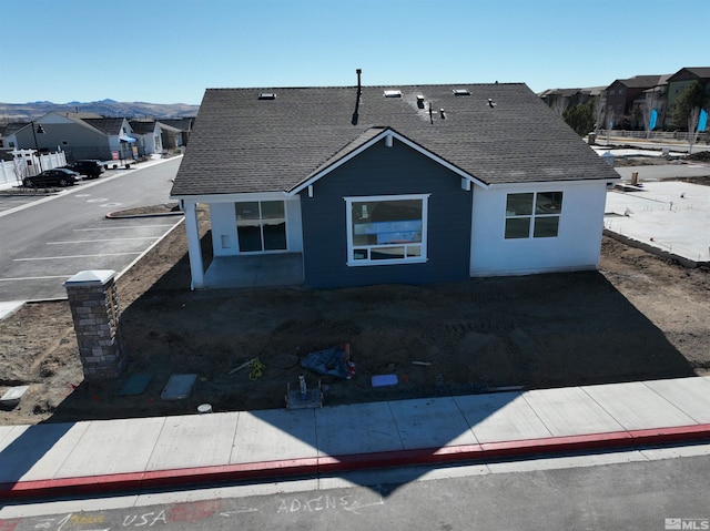 exterior space featuring roof with shingles, a residential view, and a mountain view