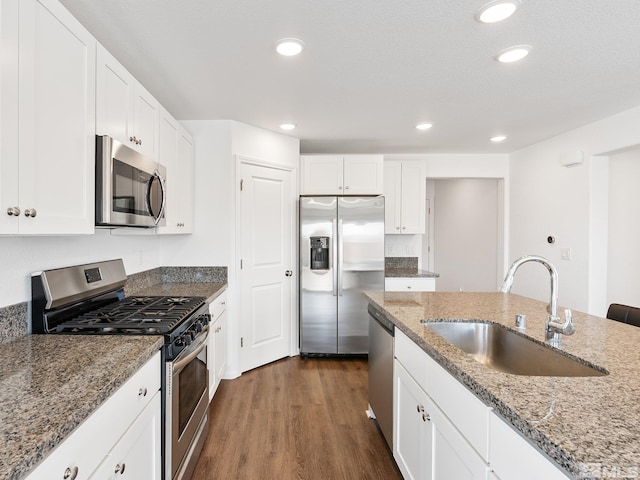 kitchen featuring dark wood-style floors, stainless steel appliances, white cabinetry, a sink, and light stone countertops