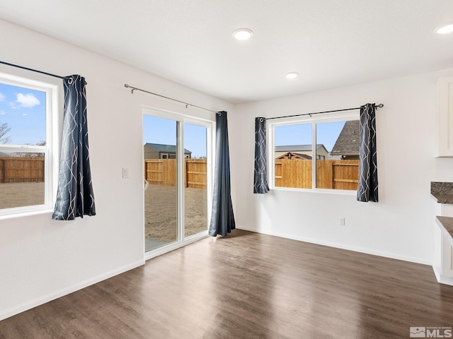 unfurnished room with dark wood finished floors, plenty of natural light, baseboards, and recessed lighting