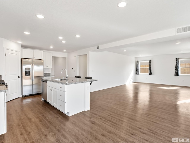 kitchen featuring visible vents, a kitchen island with sink, white cabinetry, and stainless steel appliances