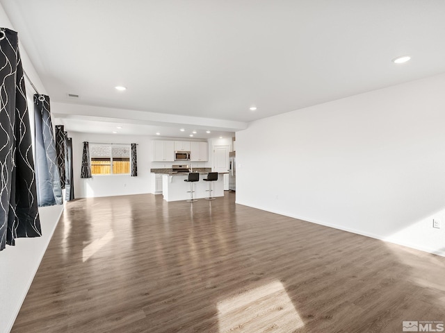 unfurnished living room with visible vents, dark wood finished floors, and recessed lighting