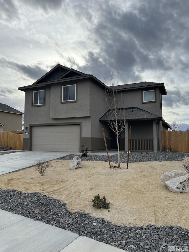 traditional-style home with concrete driveway, fence, an attached garage, and stucco siding