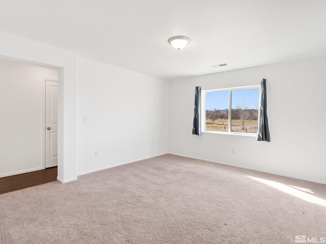 spare room with baseboards, visible vents, and carpet flooring