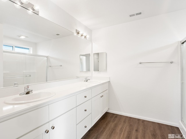 bathroom with wood finished floors, a sink, visible vents, and a shower stall