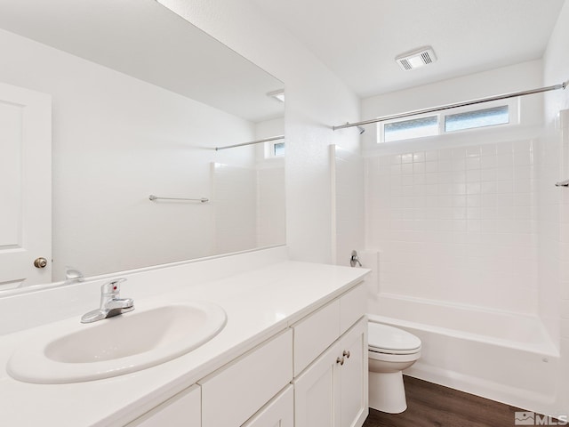 full bathroom featuring visible vents, toilet, vanity, wood finished floors, and  shower combination