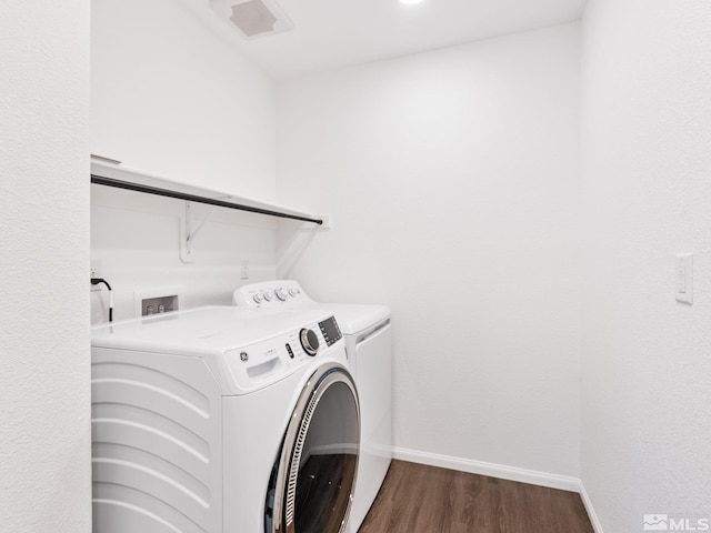 laundry area featuring dark wood-style flooring, washing machine and clothes dryer, visible vents, laundry area, and baseboards