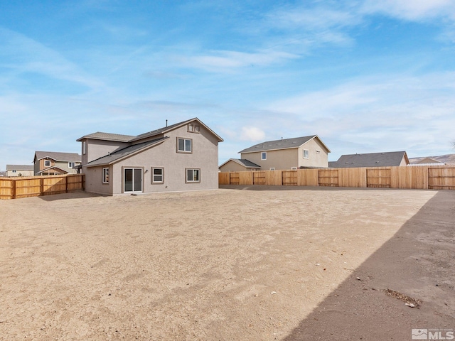 back of house featuring a fenced backyard and stucco siding