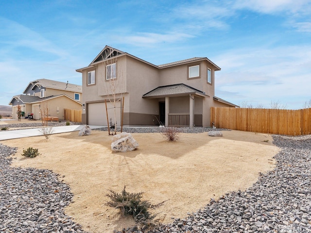 traditional home with a garage, driveway, fence, and stucco siding