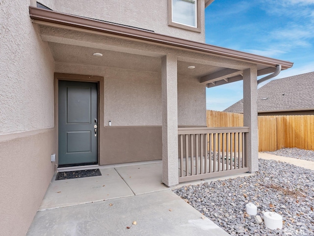 entrance to property with fence and stucco siding