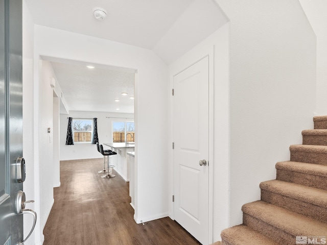 hallway with dark wood-style floors, baseboards, and stairway