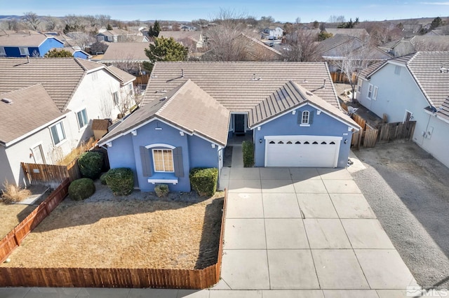 view of front of property featuring driveway, a residential view, fence, and stucco siding