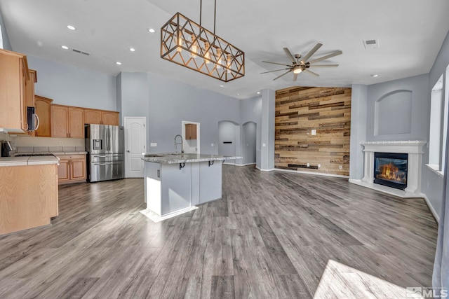 kitchen featuring stainless steel appliances, visible vents, hanging light fixtures, open floor plan, and a kitchen island with sink