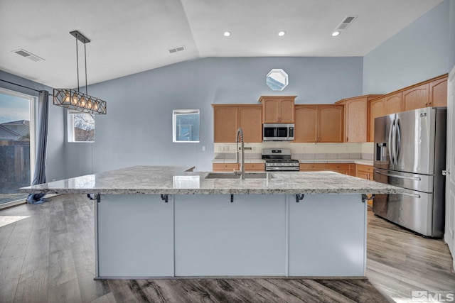 kitchen with a center island with sink, stainless steel appliances, visible vents, a sink, and light wood-type flooring