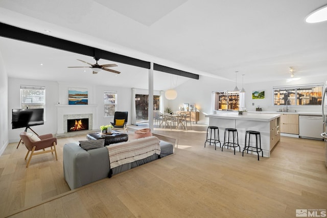 living room with light wood-style floors, a lit fireplace, and beam ceiling